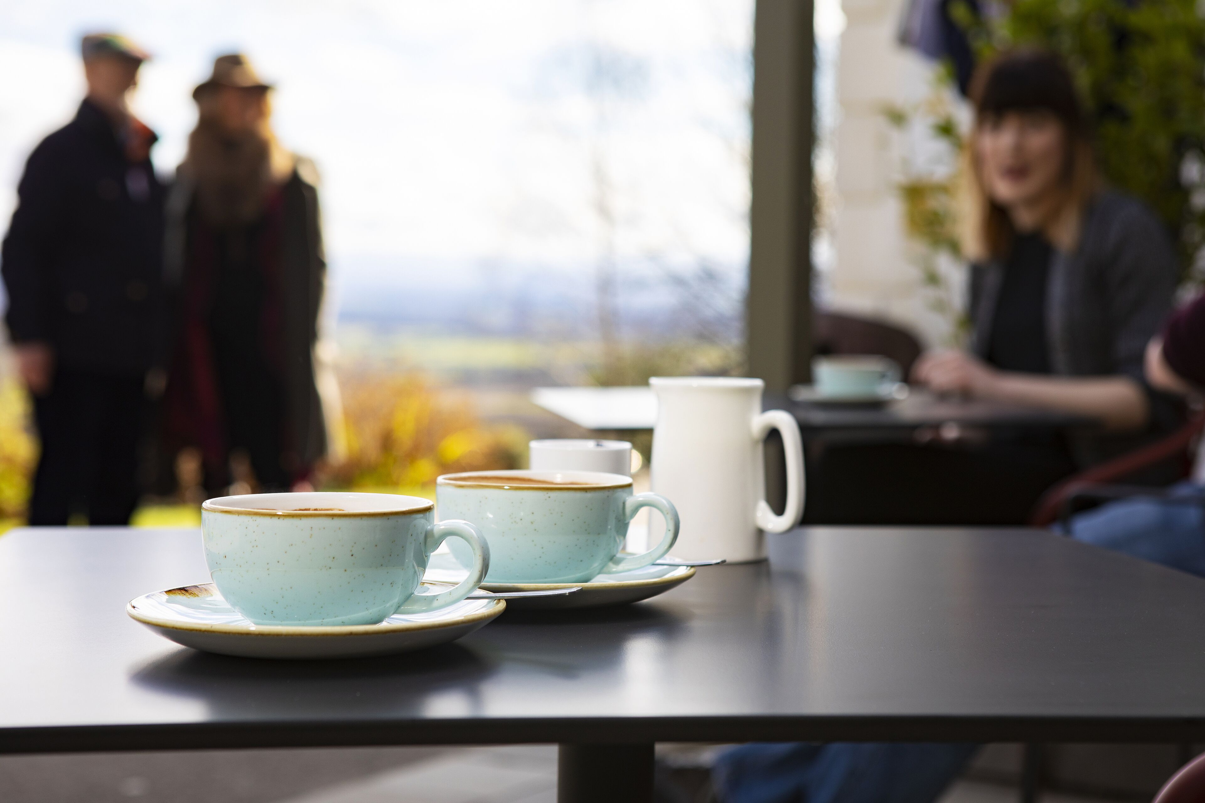 A table with two cups and a mug, likely in a cafe setting.