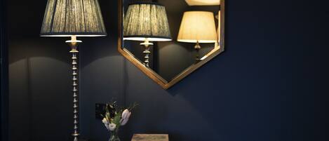 A lamp with a textured shade, a vase with flowers, and a book titled "Trees and Shrubs" on a dark surface.