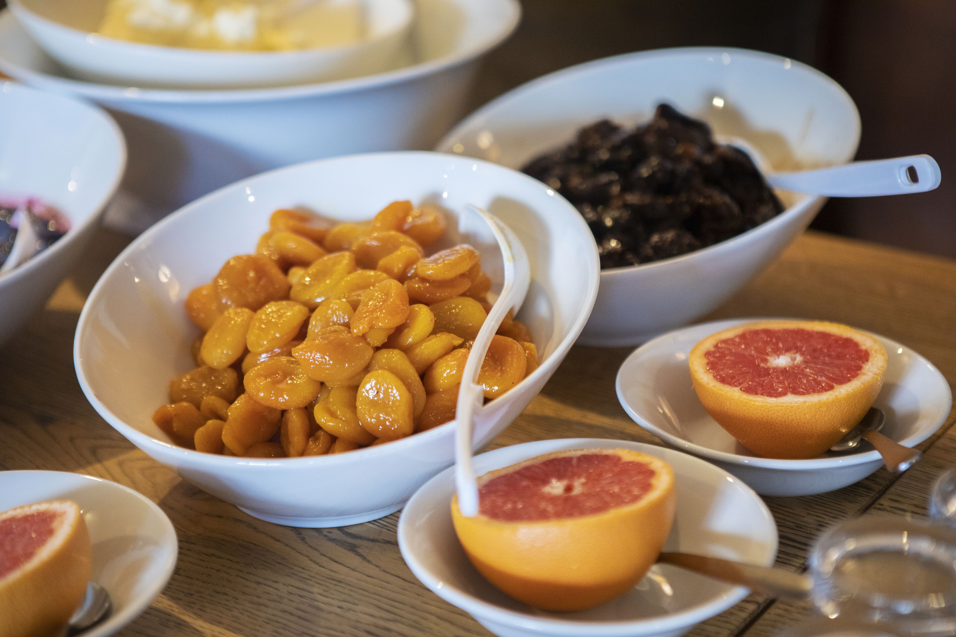 A table with various bowls containing fruits and a spoon.