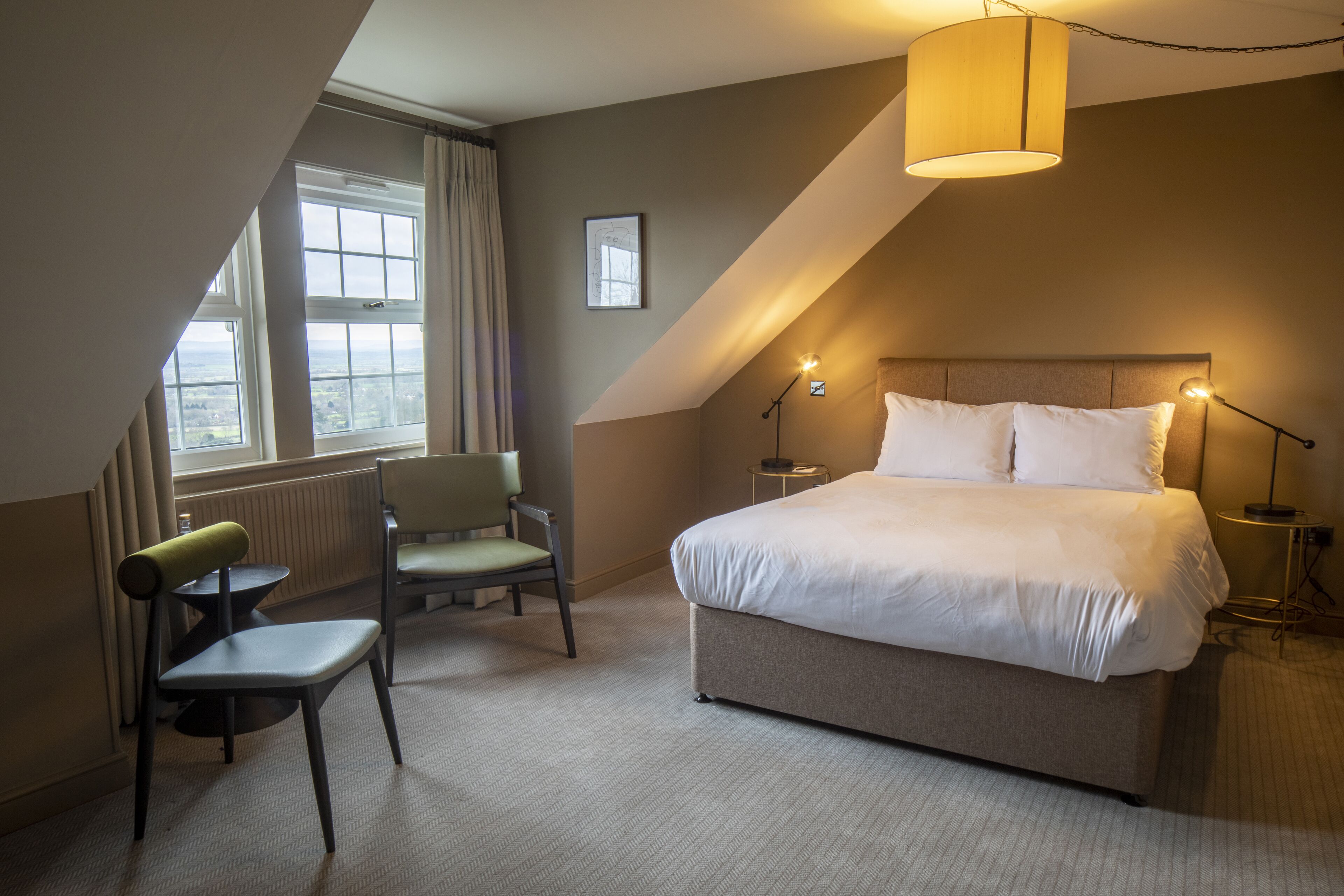 A bedroom with a bed, a chair, a lamp, a window, and a picture on the wall.