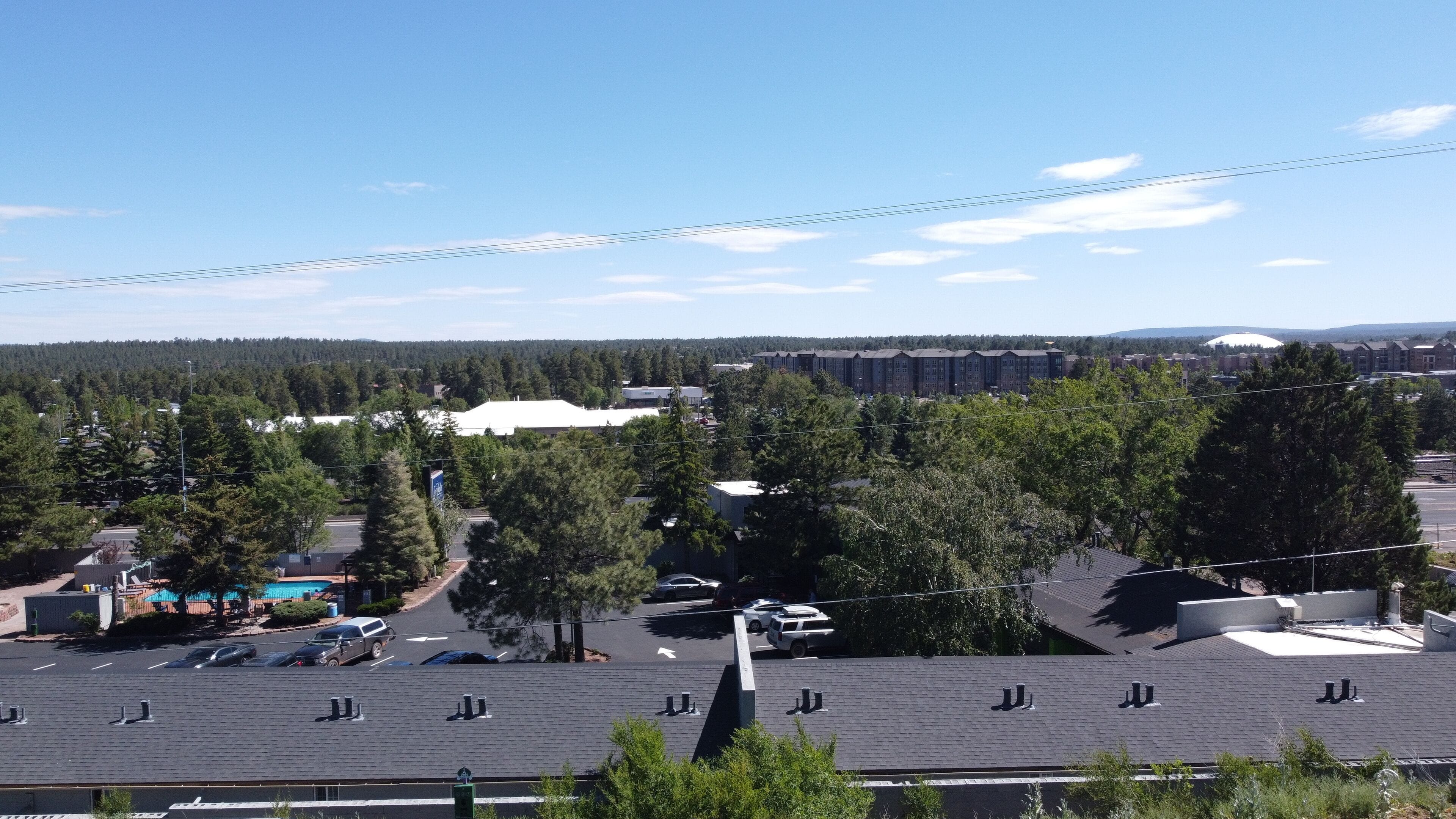 A parking lot with multiple cars, surrounded by trees and buildings.