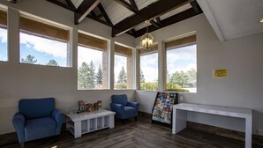 Una habitación con dos sillones azules, un banco blanco y un tablón de anuncios.