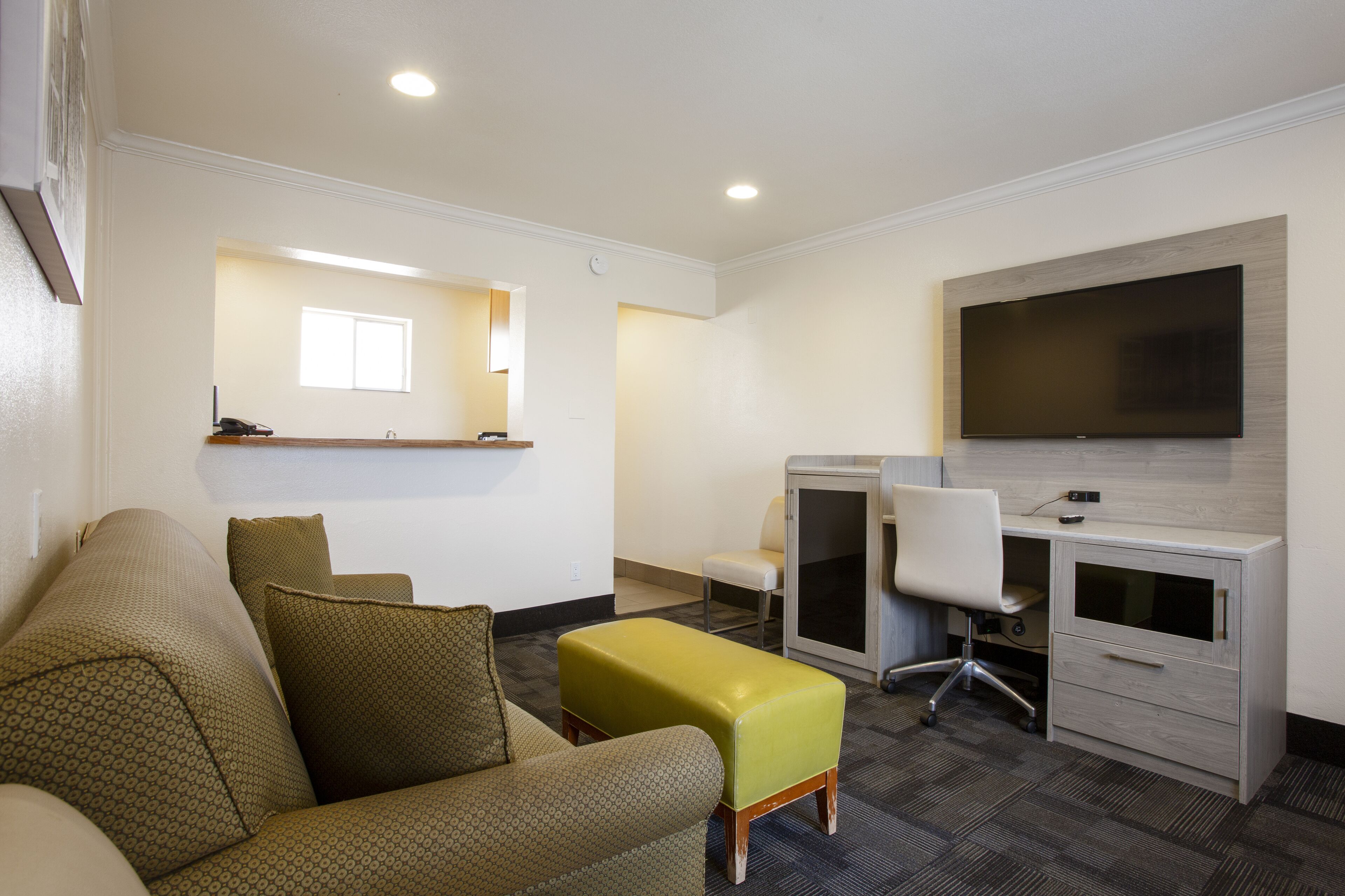 Une chambre d’hôtel moderne équipée d ’un canapé, d’une petite table, d’un bureau avec une chaise, d’une télévision et d’une fenêtre.