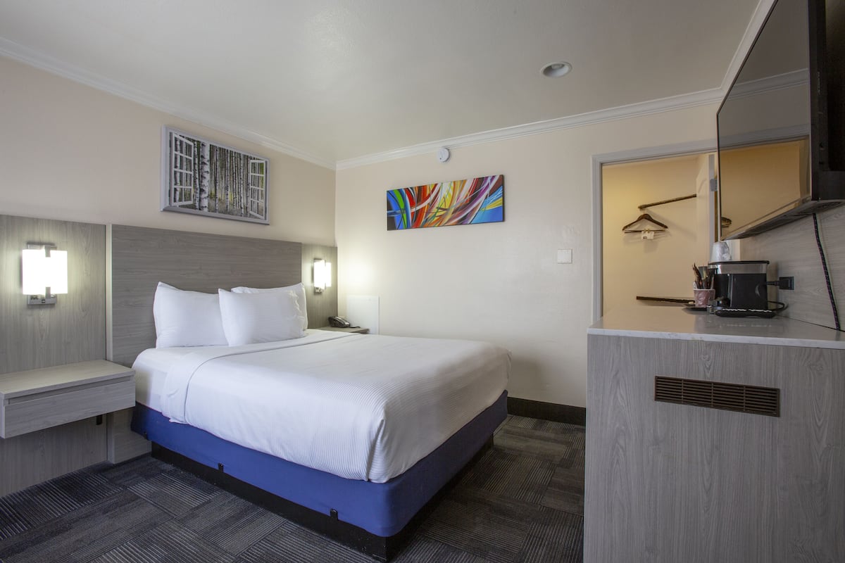 Habitación de hotel con una cama grande, mesitas de noche, un escritorio y un espejo.