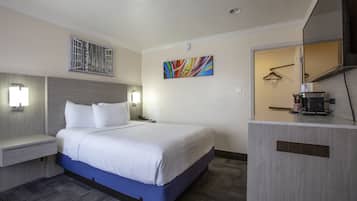 A hotel room with a large bed, bedside tables, a desk, and a mirror.
