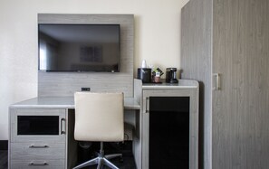 Una habitación de hotel con escritorio, silla, televisor y minibar.