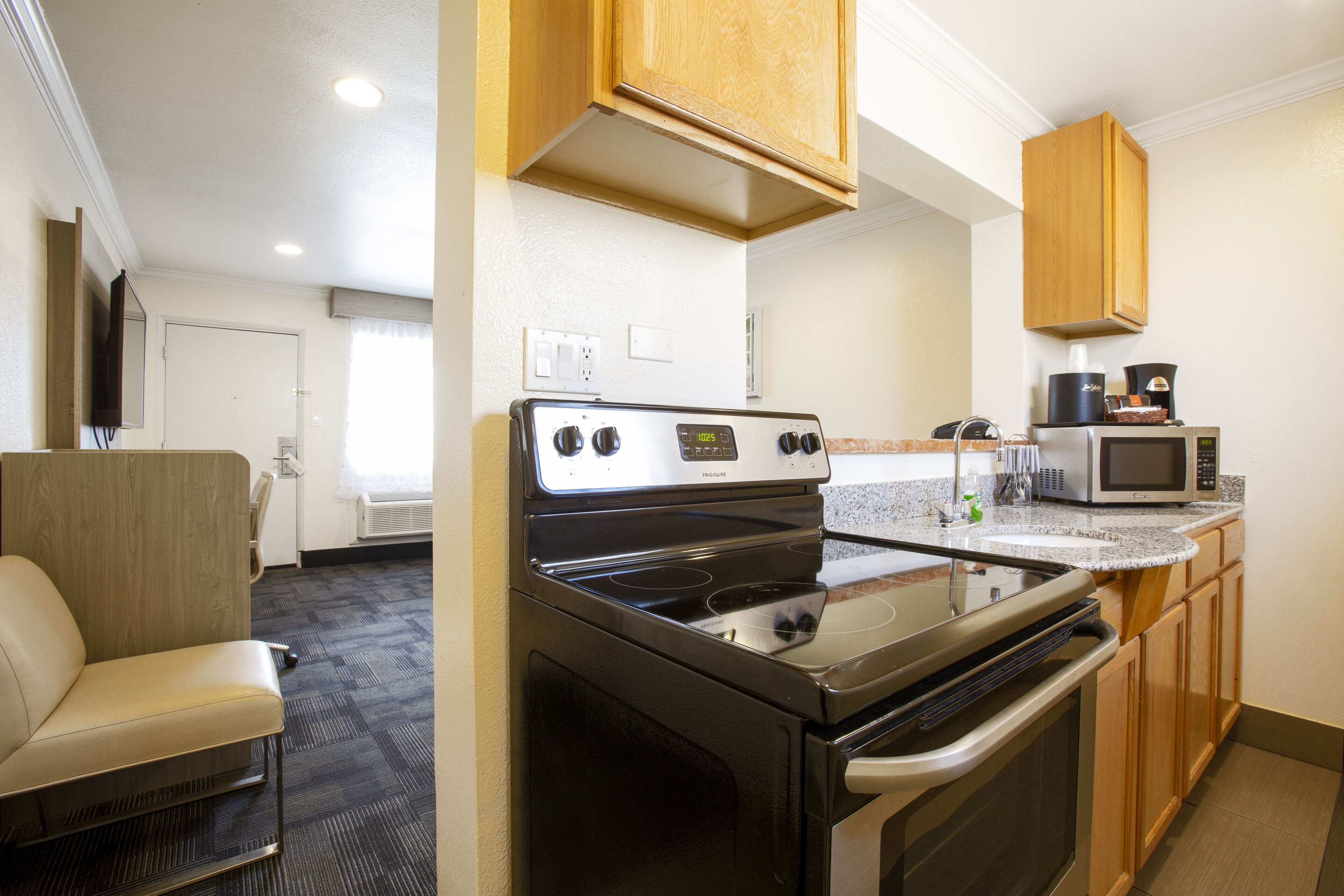 A compact kitchen with a stove, microwave, and wooden cabinets.