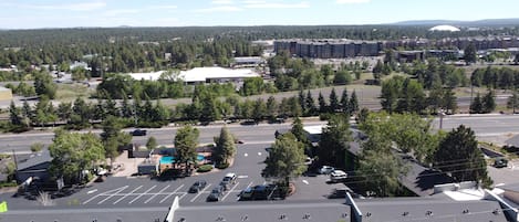 A parking lot with multiple rows of parking spaces, a swimming pool, and a building with a flat roof in the background.