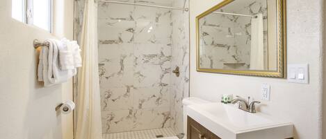 Une salle de bain équipée d’une douche, de toilettes, d’un lavabo et d’un miroir avec un cadre doré.