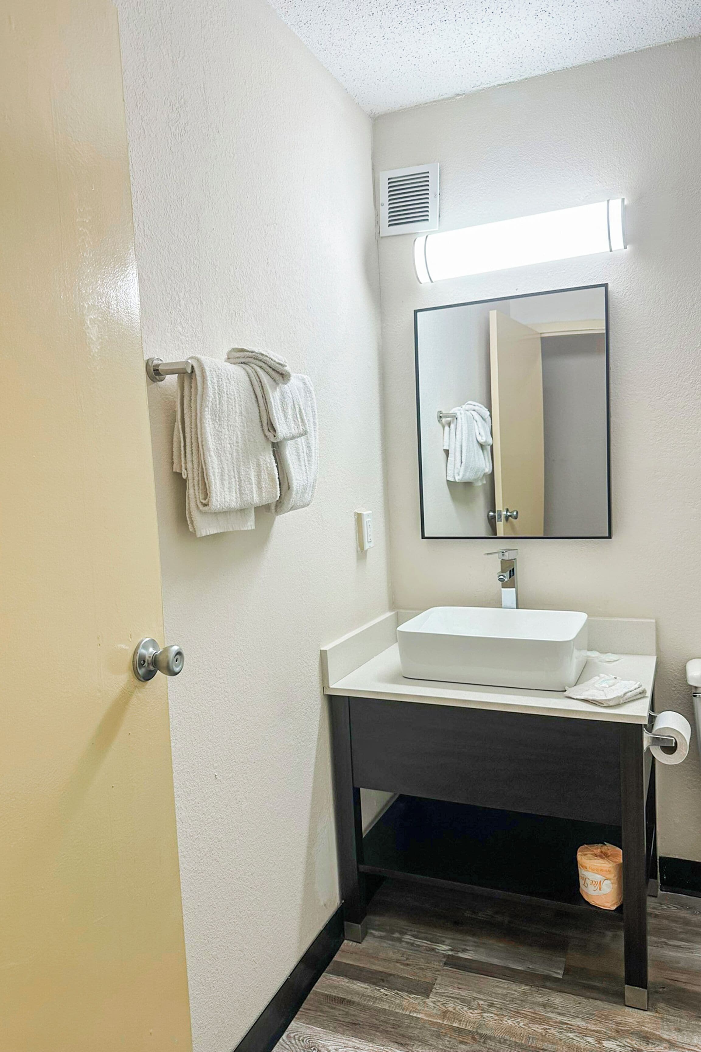 Une salle de bain avec un lavabo blanc, un miroir et un porte-serviettes.