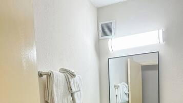 Une salle de bain avec un lavabo blanc, un miroir et un porte-serviettes.
