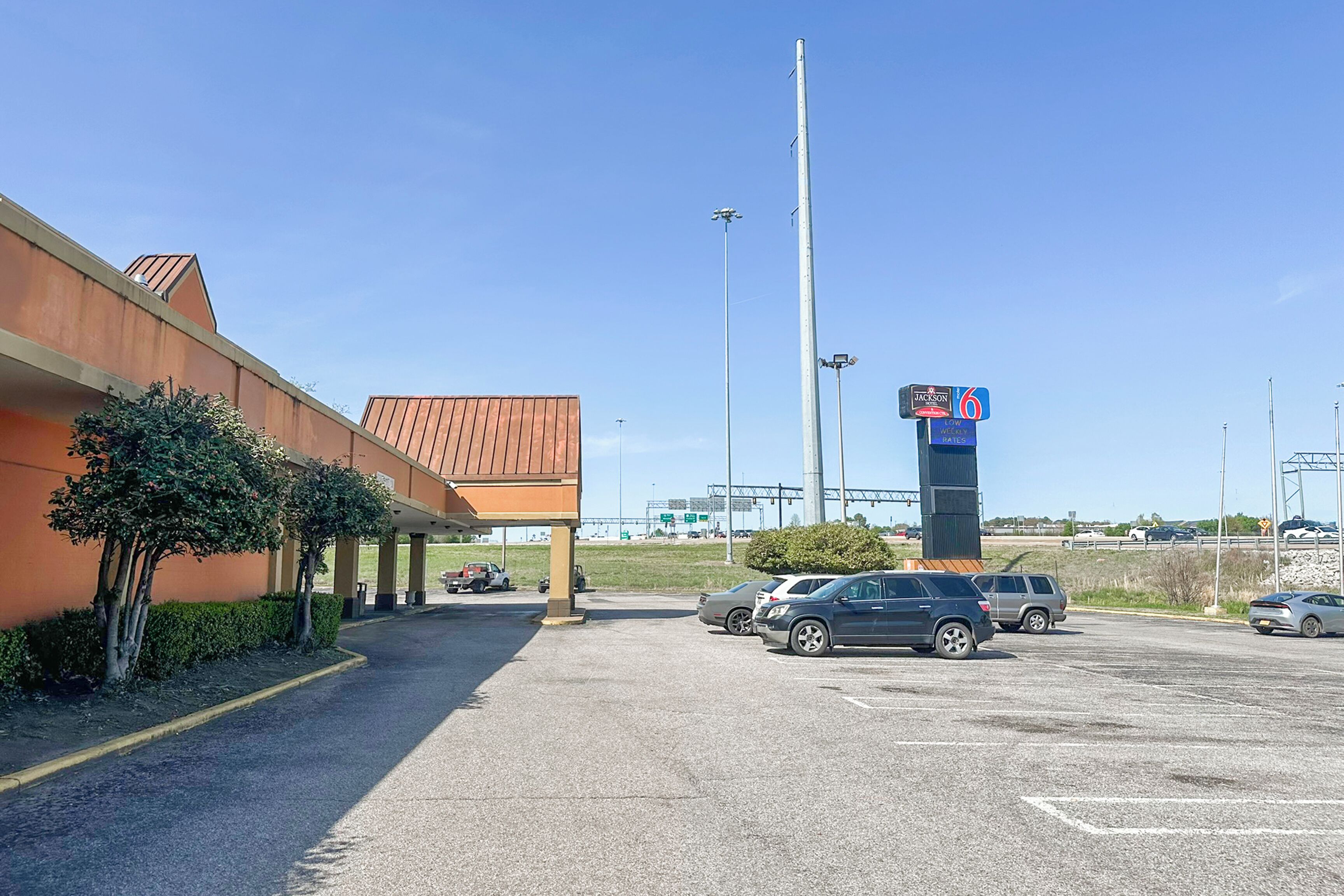 A parking lot with several cars, a building with a brown roof, and a sign for 'Jackson 6'.