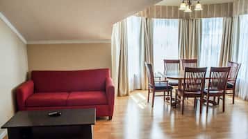 A living room with a red sofa, a dark coffee table, and a dining area with wooden chairs and a table.