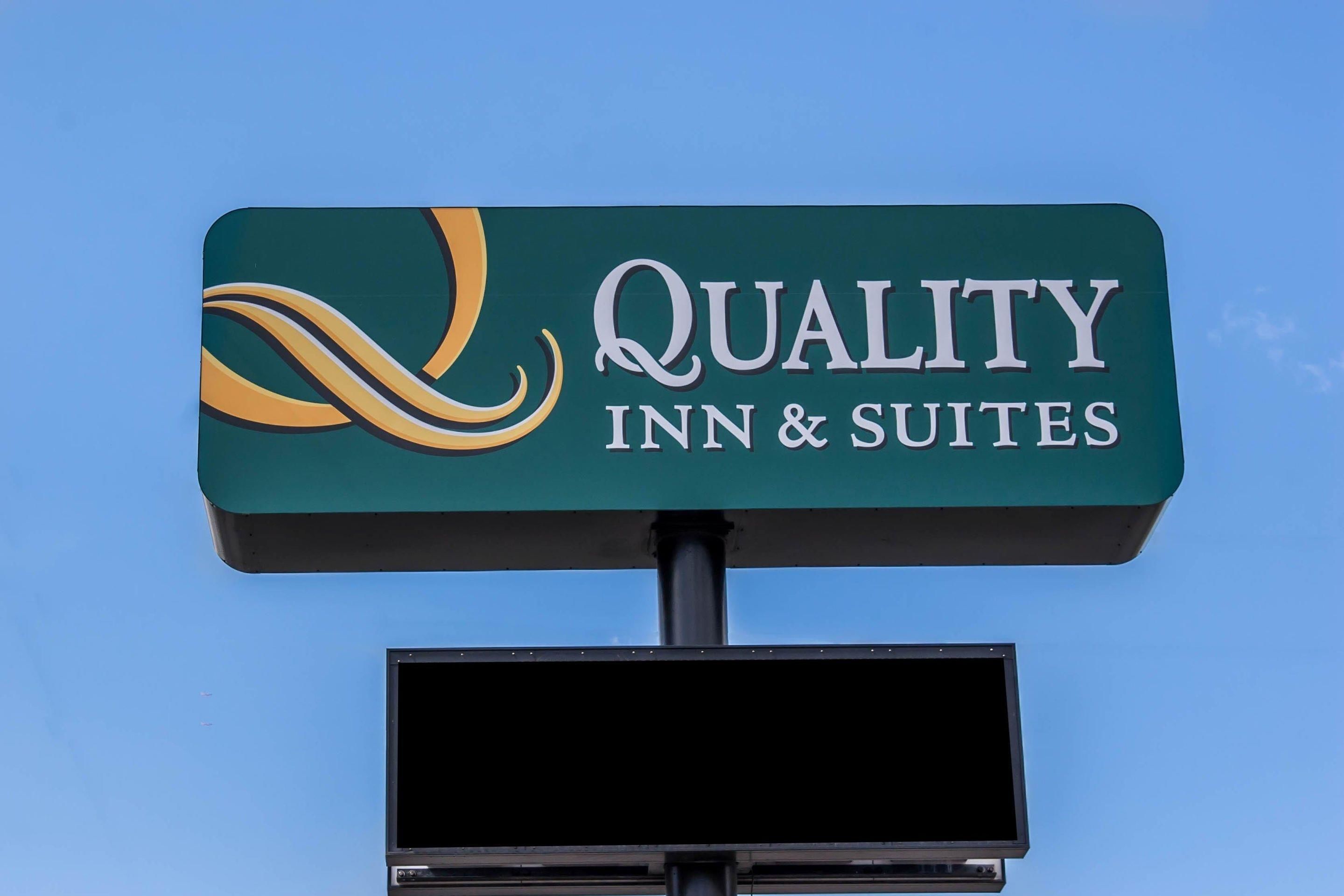A sign for Quality Inn & Suites with a stylized logo and text.