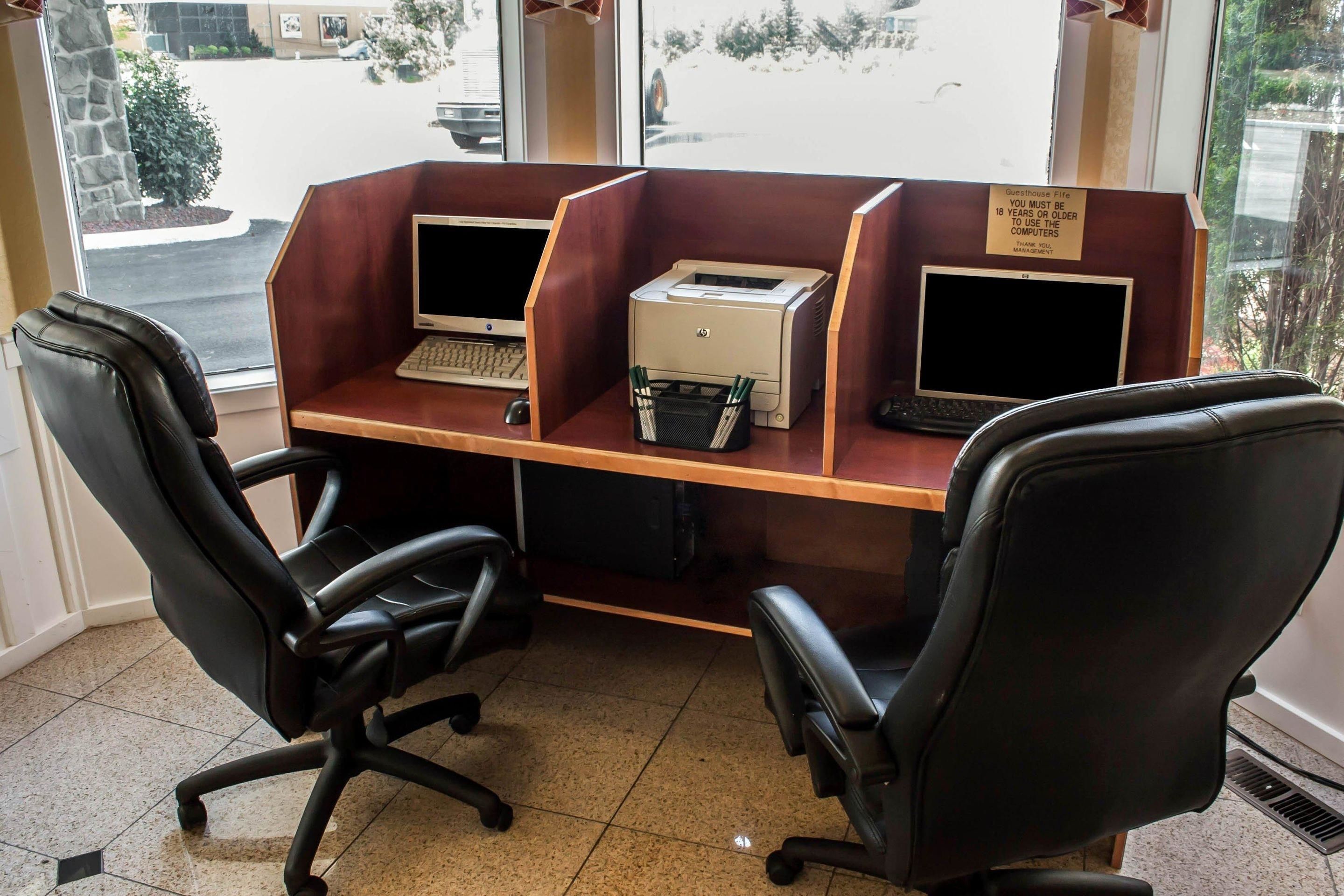 A cubicle office with two desks, each with a computer and printer.