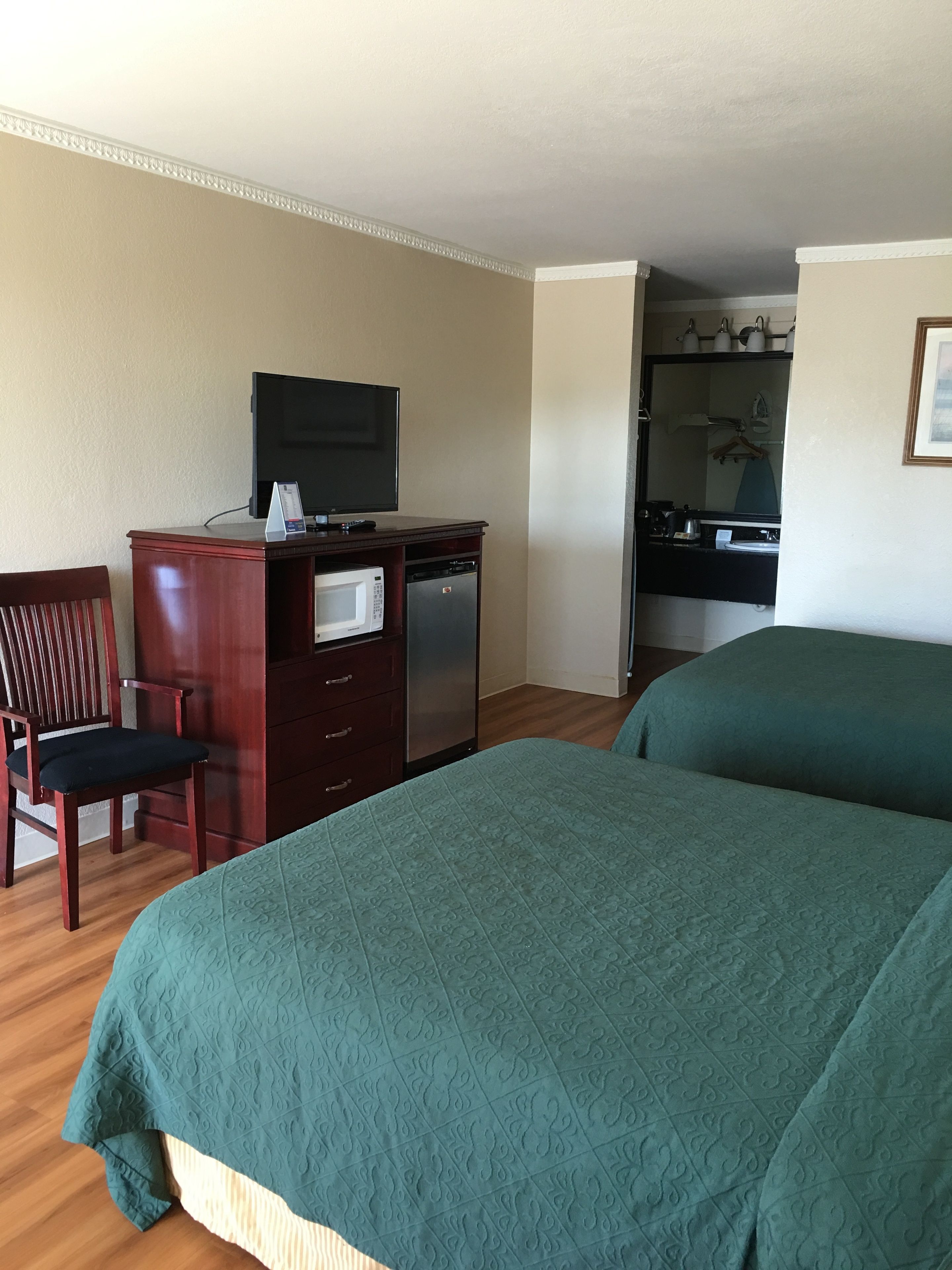 Habitación de hotel con dos camas, un escritorio, televisión, microondas y refrigerador.