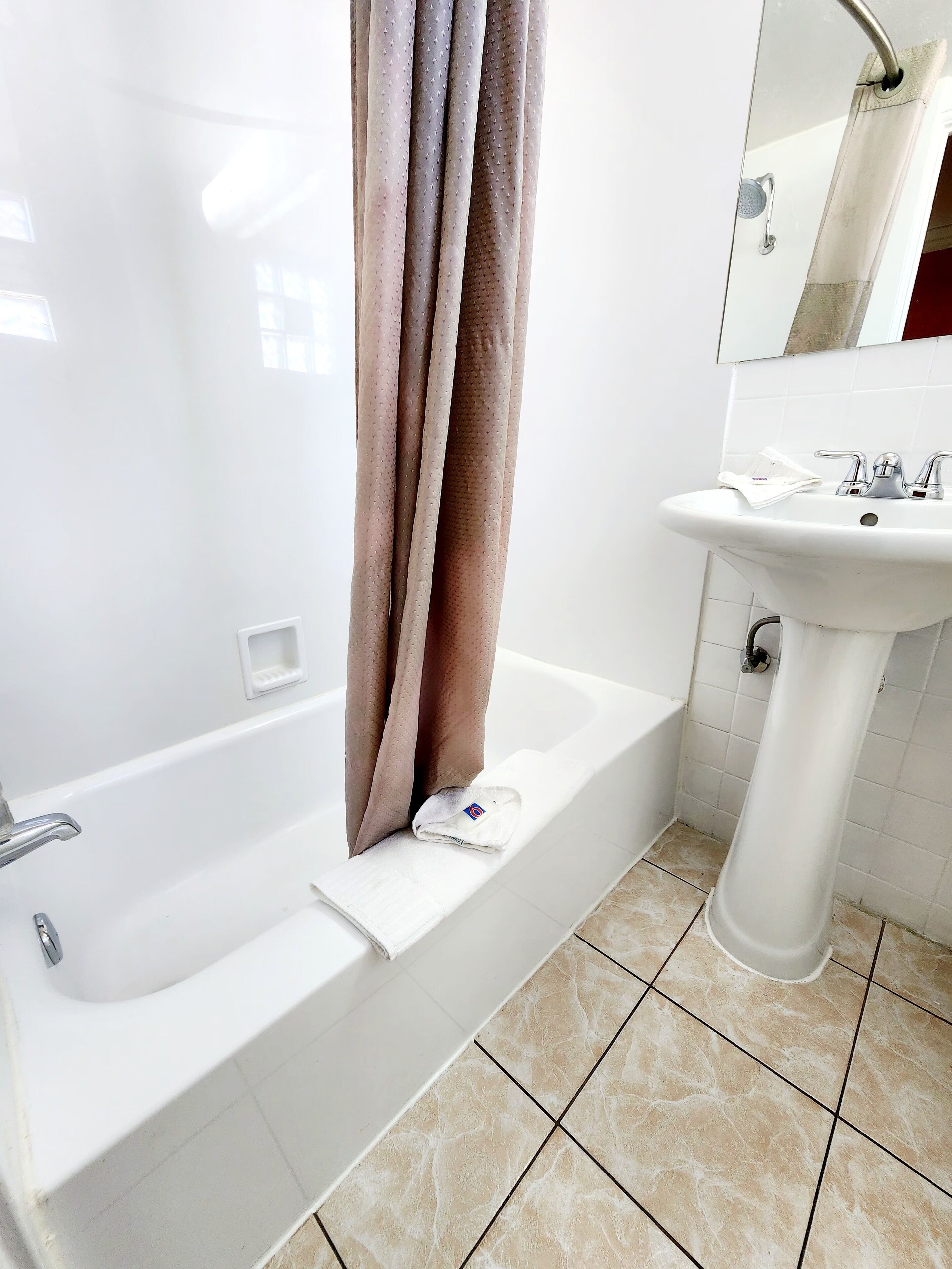 A bathroom with a bathtub, a sink, and a shower curtain.