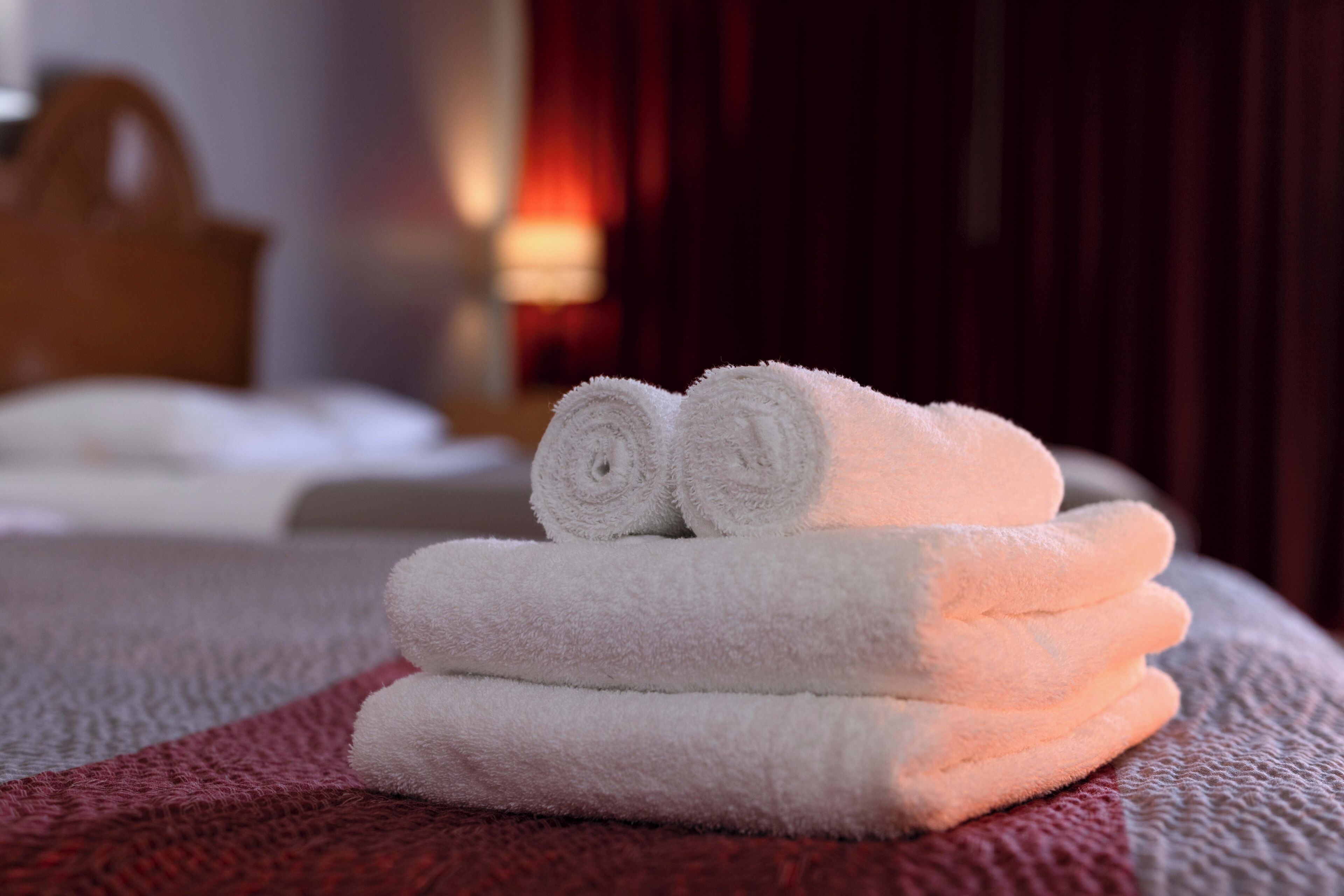 A neatly folded stack of white towels on a bed.