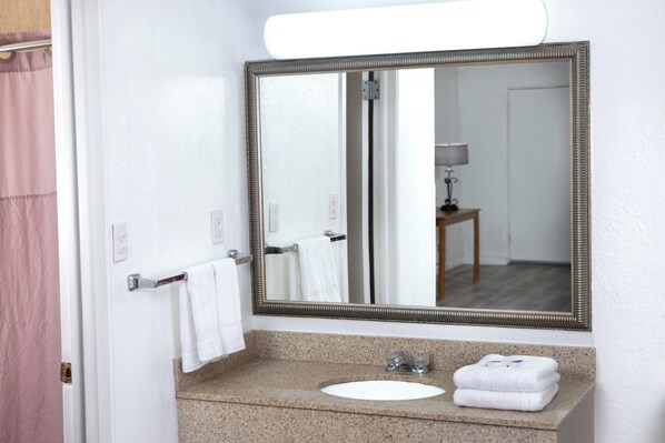 A bathroom with a sink, mirror, and towel rack.