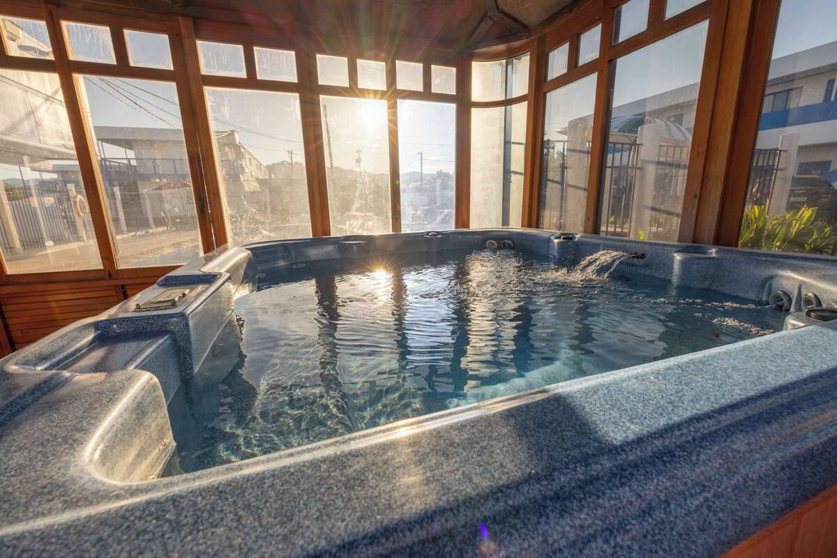 A hot tub with a view of buildings through large windows.