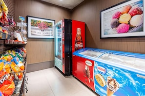 Uma área de máquinas de venda automática com lanches, um refrigerador de Coca-Cola e um congelador de Häagen-Dazs.