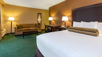Een hotelkamer met een groot bed, een bank, twee lampen, een bureau en een telefoon.