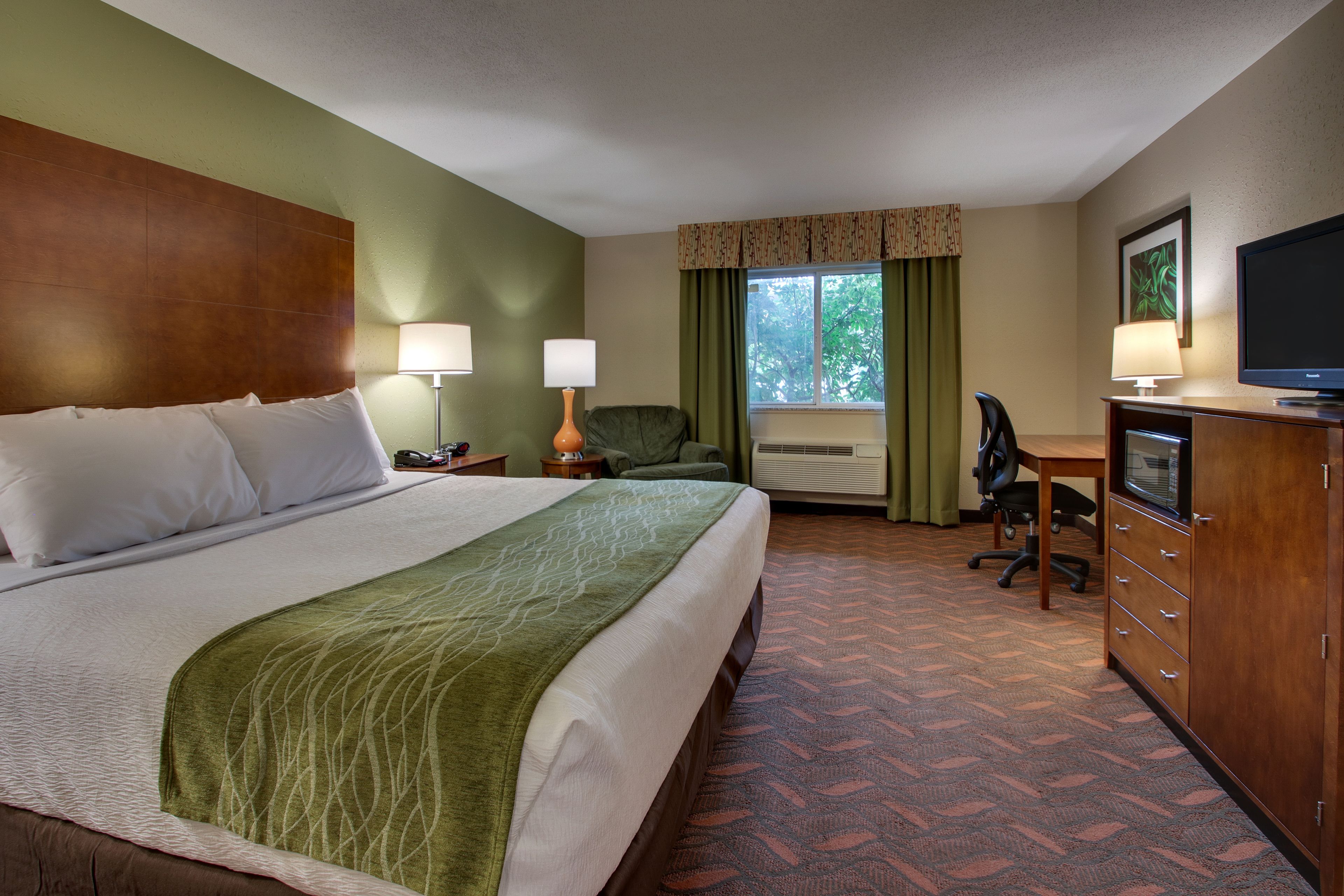Une chambre d’hôtel avec un grand lit, un bureau, une chaise, une télévision et une armoire.