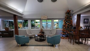 A spacious living area with two armchairs, a coffee table, and a Christmas tree. - Greenfield Inn and Suites Elizabethtown, KY I65 Exit 94 (Elizabethtown)