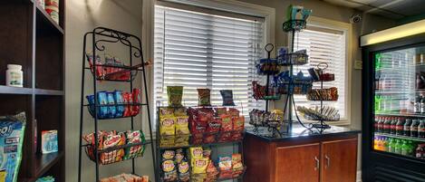 A snack display with various chips and snacks, a beverage refrigerator, and a window with blinds.