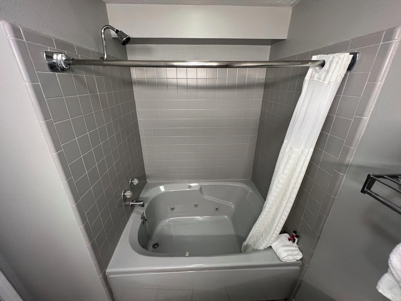 Un baño pequeño y moderno con una bañera, un cortinón de ducha y un perchero para toallas.