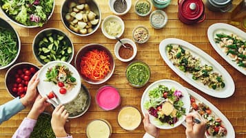 A variety of dishes and ingredients spread across a wooden table, suggesting a meal preparation or buffet setting.