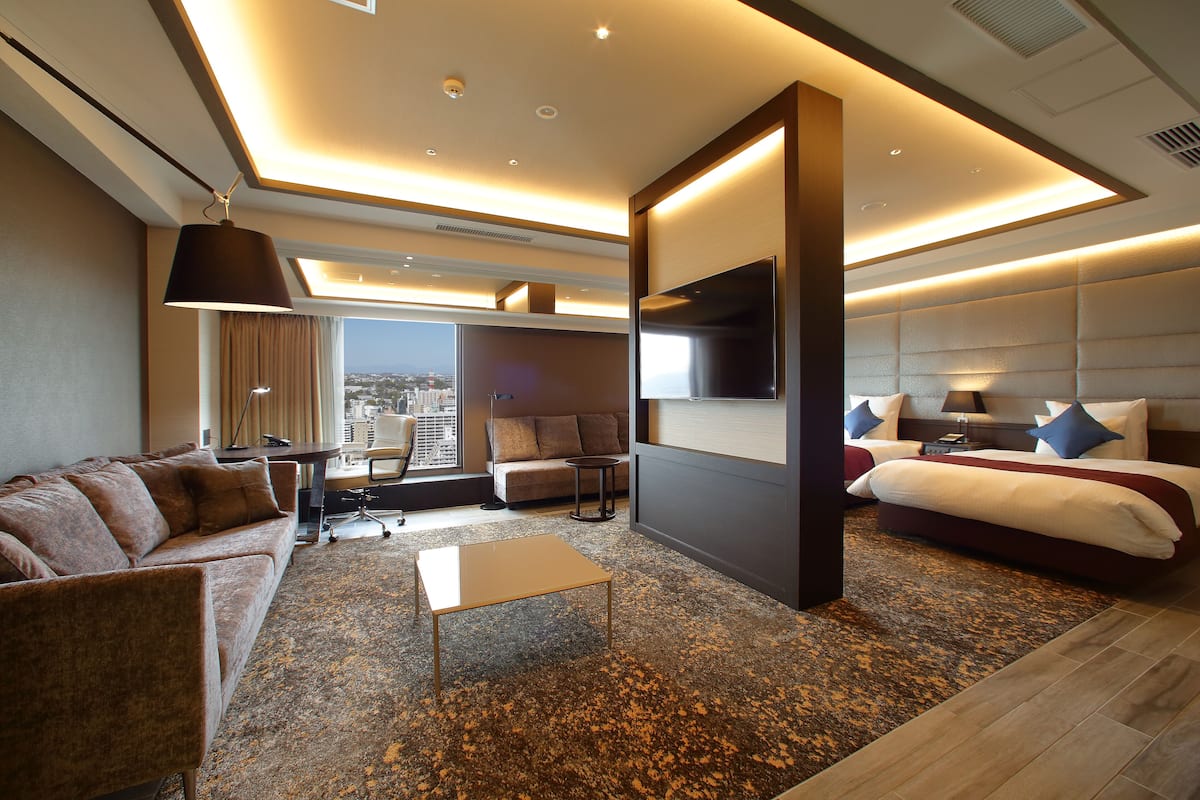 Ein modernes Hotelzimmer mit einem großen Bett, einer Couch, einem Couchtisch und einem Fernseher.