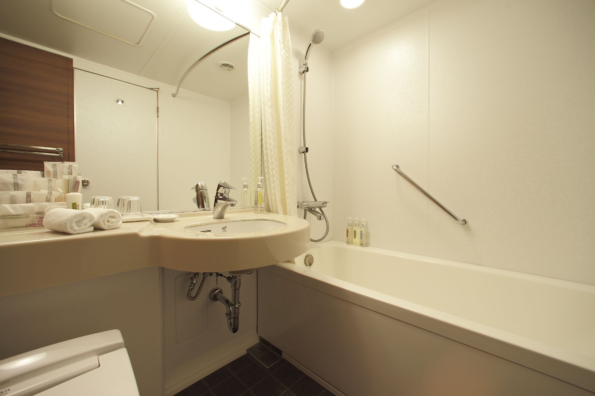 A bathroom with a sink, mirror, shower, and toilet.