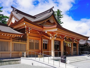 Il s’agit d’un bâtiment japonais traditionnel, doté d’un toit incurvé, de piliers en bois et d’un escalier en pierre menant à l’entrée.