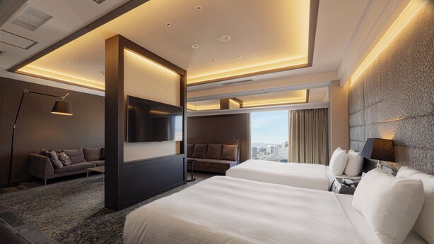 Una habitación de hotel moderna con dos camas, un sofá, un televisor y vistas a la ciudad.