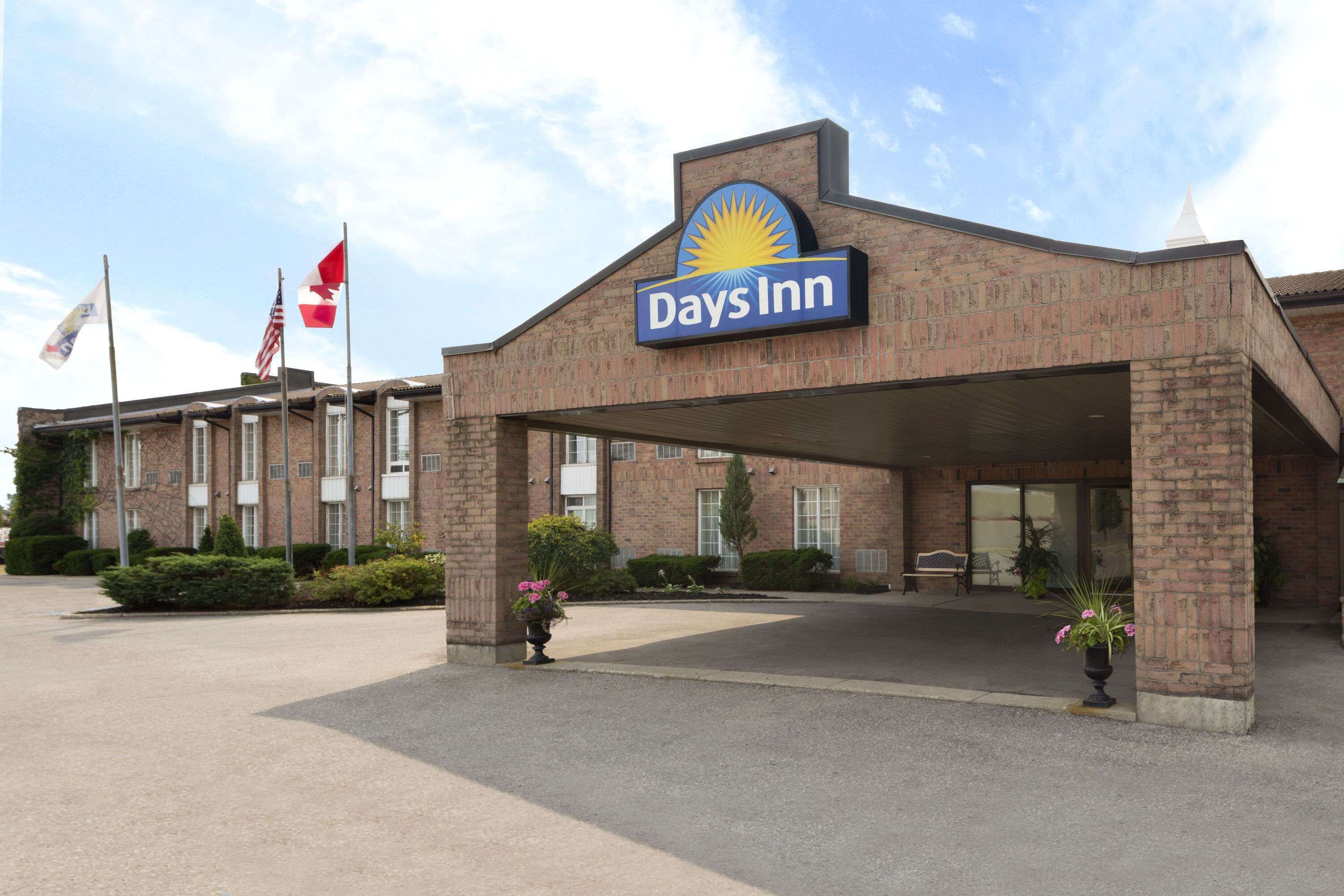 A Days Inn building with a brick facade, a large entrance canopy, and a clear sky.