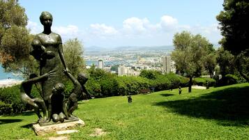 A statue in a park with a cityscape in the background.