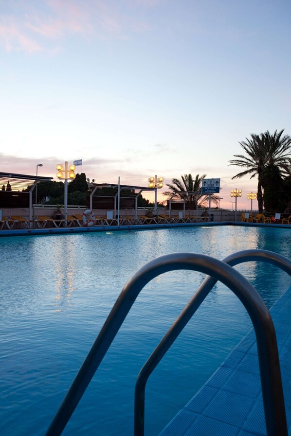 Una piscina al aire libre de temporada, sombrillas