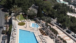 Une piscine sur le toit, dotée de chaises longues et offrant une vue sur la ville et la mer.