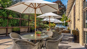 An outdoor patio with wicker furniture, white umbrellas, and hanging plants.