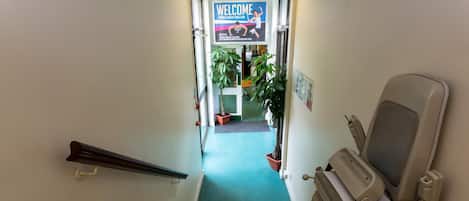 A stairway leading to a room with a massage chair and a welcome sign for a health club.