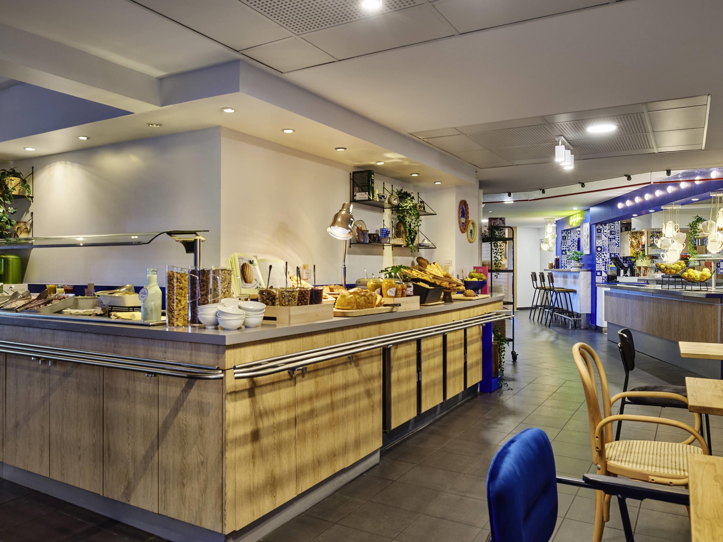 Una cafetería moderna con mostrador de madera, zona de estar y detalles decorativos.
