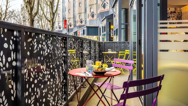 A balcony with a table and chairs, a decorative fence, and a building in the background. - ibis Paris La Villette Cité des Sciences 19ème (Paris)