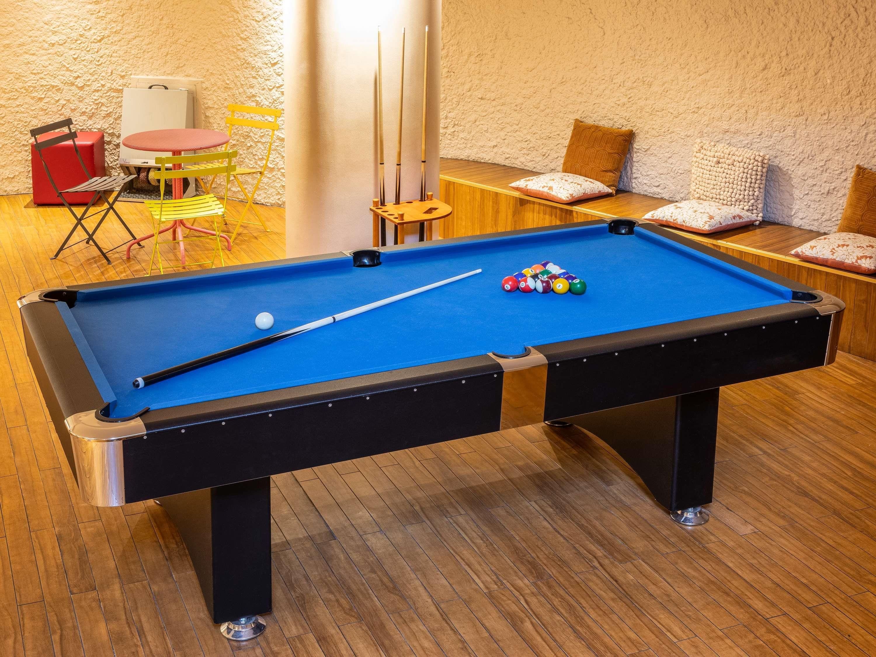 A pool table with a blue felt surface, a pool cue, and colorful balls.