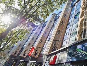 Moderni hotellirakennus, jossa on useita kerroksia, suuret ikkunat ja selkeästi näkyvä punainen kyltti, josta ilmenee, että kyseessä on Ibis-hotelli.