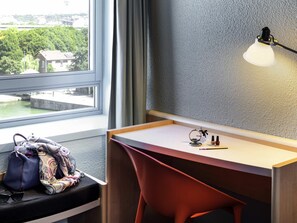 Una habitación moderna con escritorio, silla y vista a un cuerpo de agua a través de una ventana.