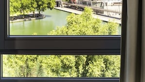 A window with a view of a river, trees, and a bridge. - ibis Paris La Villette Cité des Sciences 19ème (Paris)