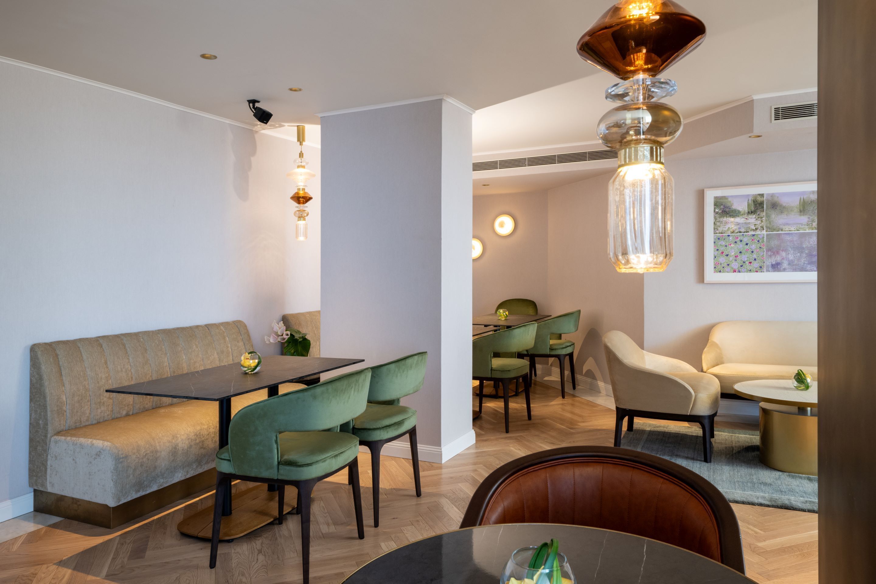 Un espace repas moderne avec une table en bois, des chaises recouvertes d’un tissu vert, un canapé beige et une table basse ronde.