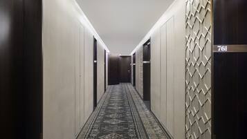 A hallway with a patterned carpet, a wall with a geometric design, and a door with the number 761.