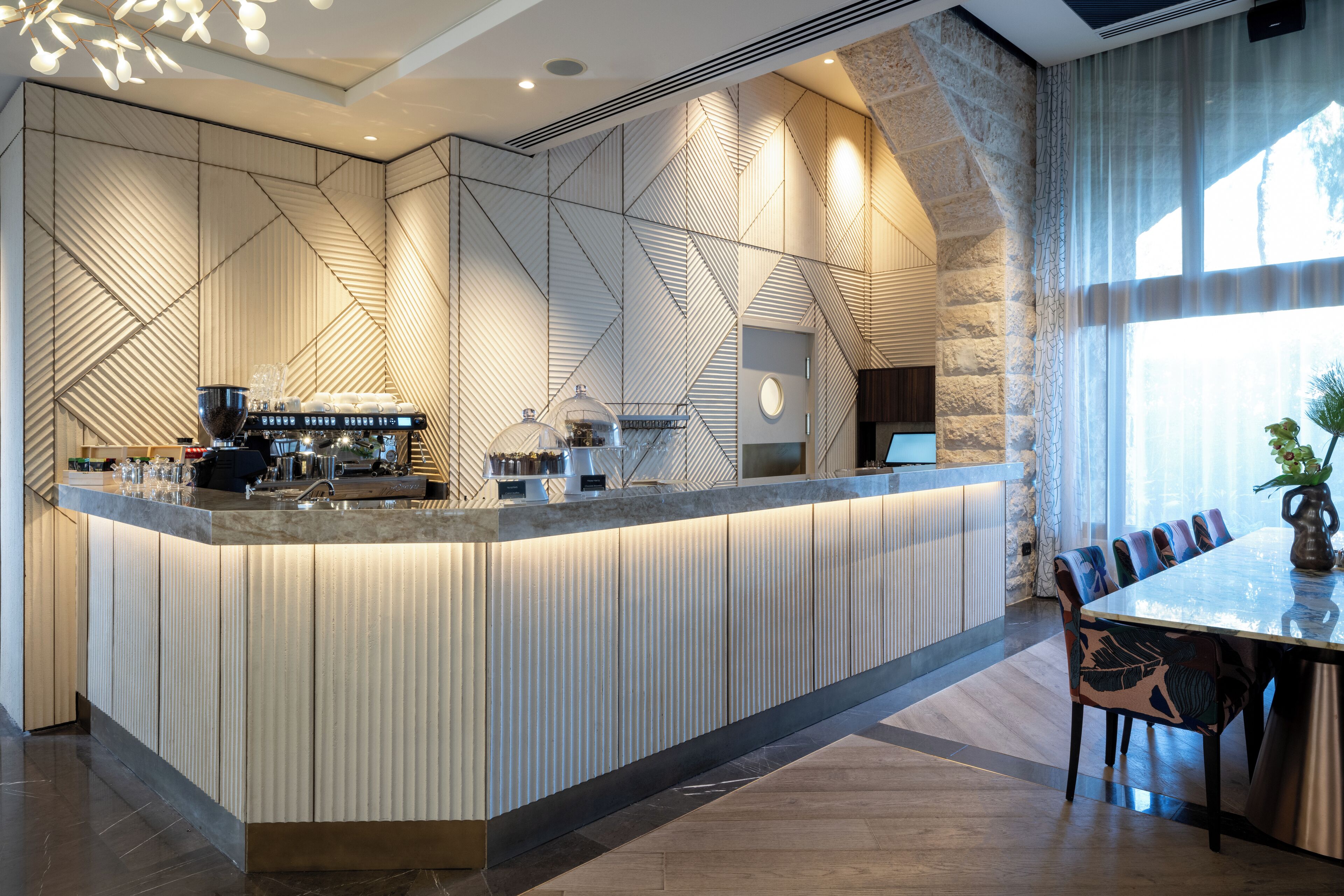 A modern bar area with a long counter, seating, and a stone wall.